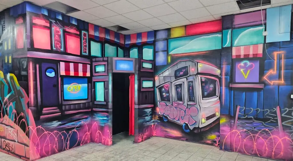 Buntes Urban-Graffiti an den Wänden der Lasertag Arena Braunsbedra mit leuchtenden Neon-Schildern und einem gezeichneten Wohnmobil.