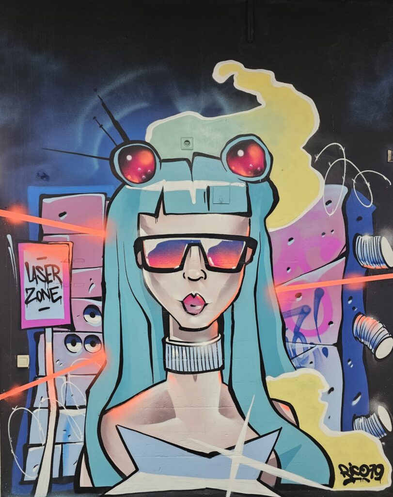 Modernes Cyberpunk-Graffiti einer Frau mit t&uuml;rkisblauen Haaren, Sonnenbrille und &bdquo;Laser Zone&ldquo;-Schild in der Lasertag Arena Braunsbedra.