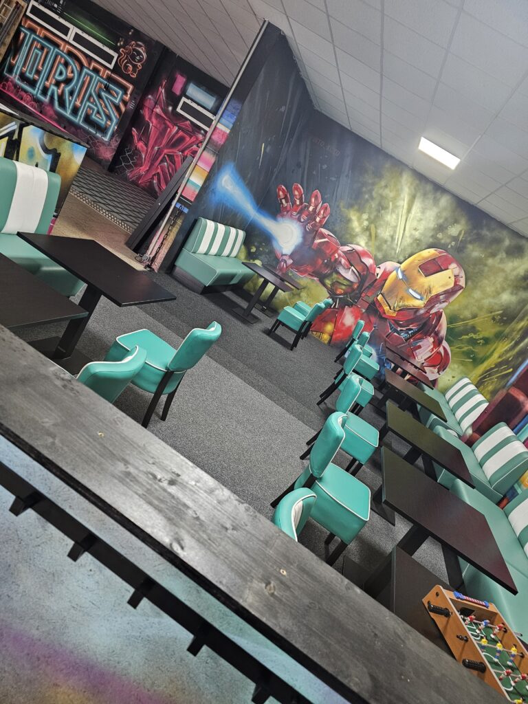 Exklusive VIP Lounge der Lasertag Arena Braunsbedra im Geiseltal mit Iron-Man-Graffiti, Tischen und Retro-Sitzb&auml;nken.
